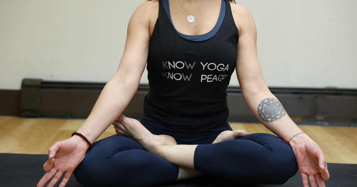 A yoga student seated cross-legged in meditation on a mat