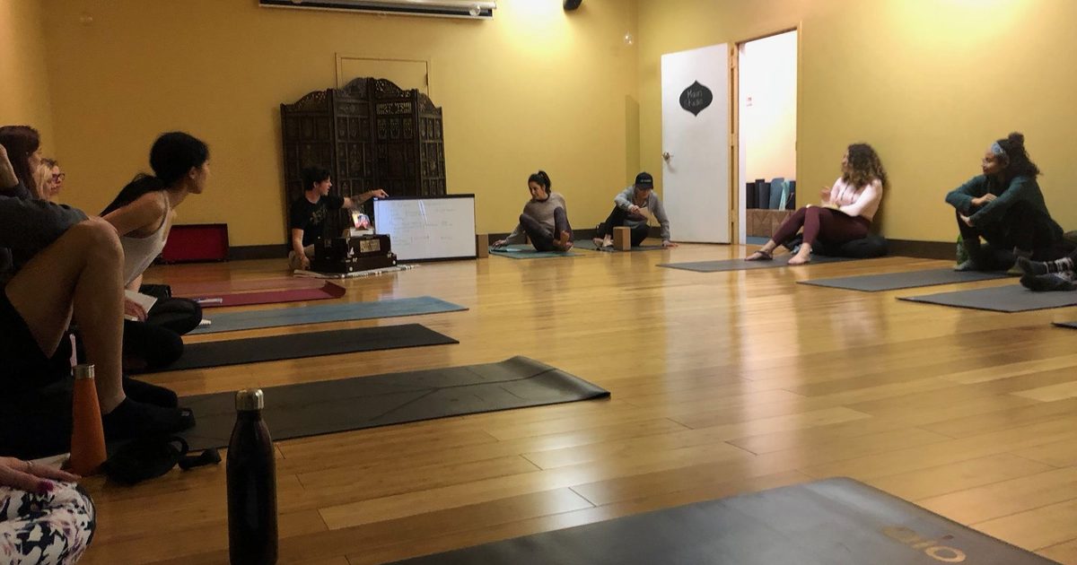 A yoga teacher offering alignment guidance in class