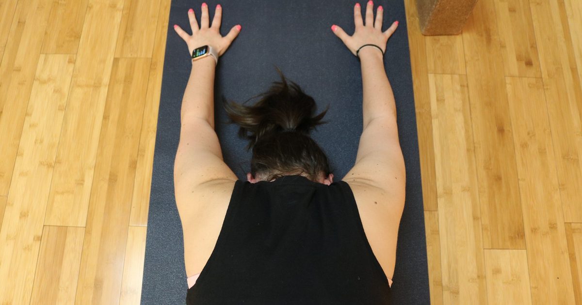A student resting forward in an extended child's pose on a yoga mat