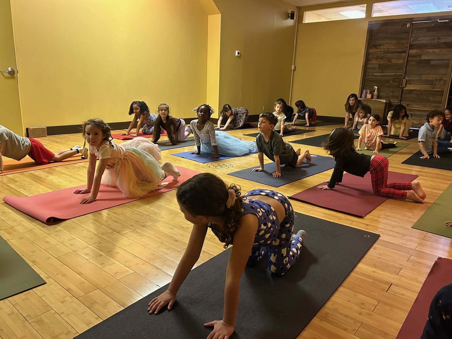 Kids in tabletop and cat-cow poses at a yoga art party