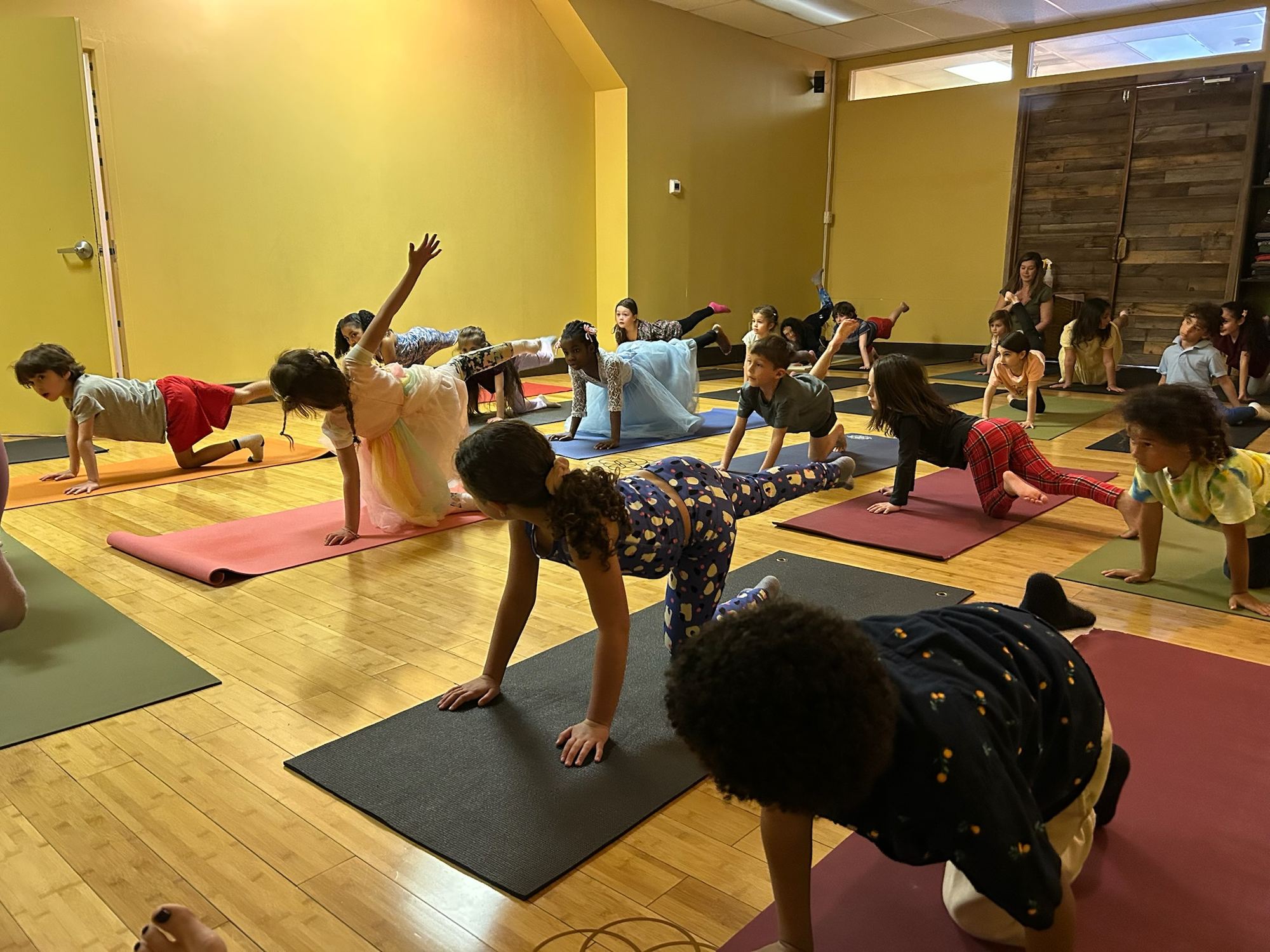 Kids balancing in bird-dog pose at a yoga spa party