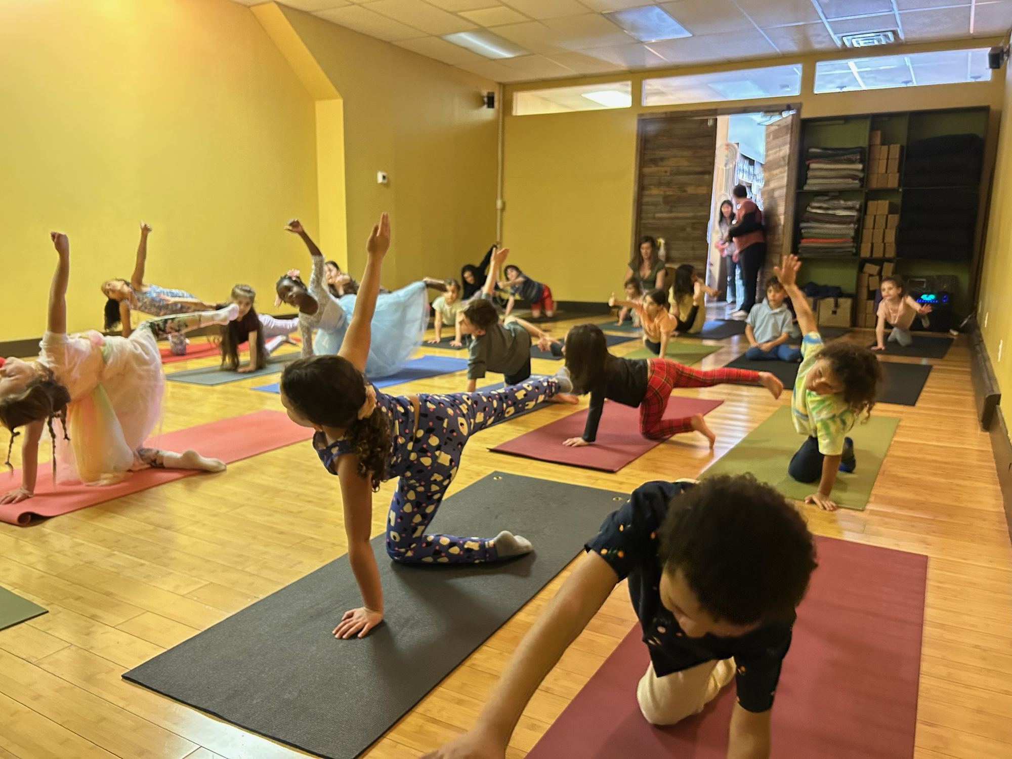 Children stretching one arm and leg during a butterfly yoga party