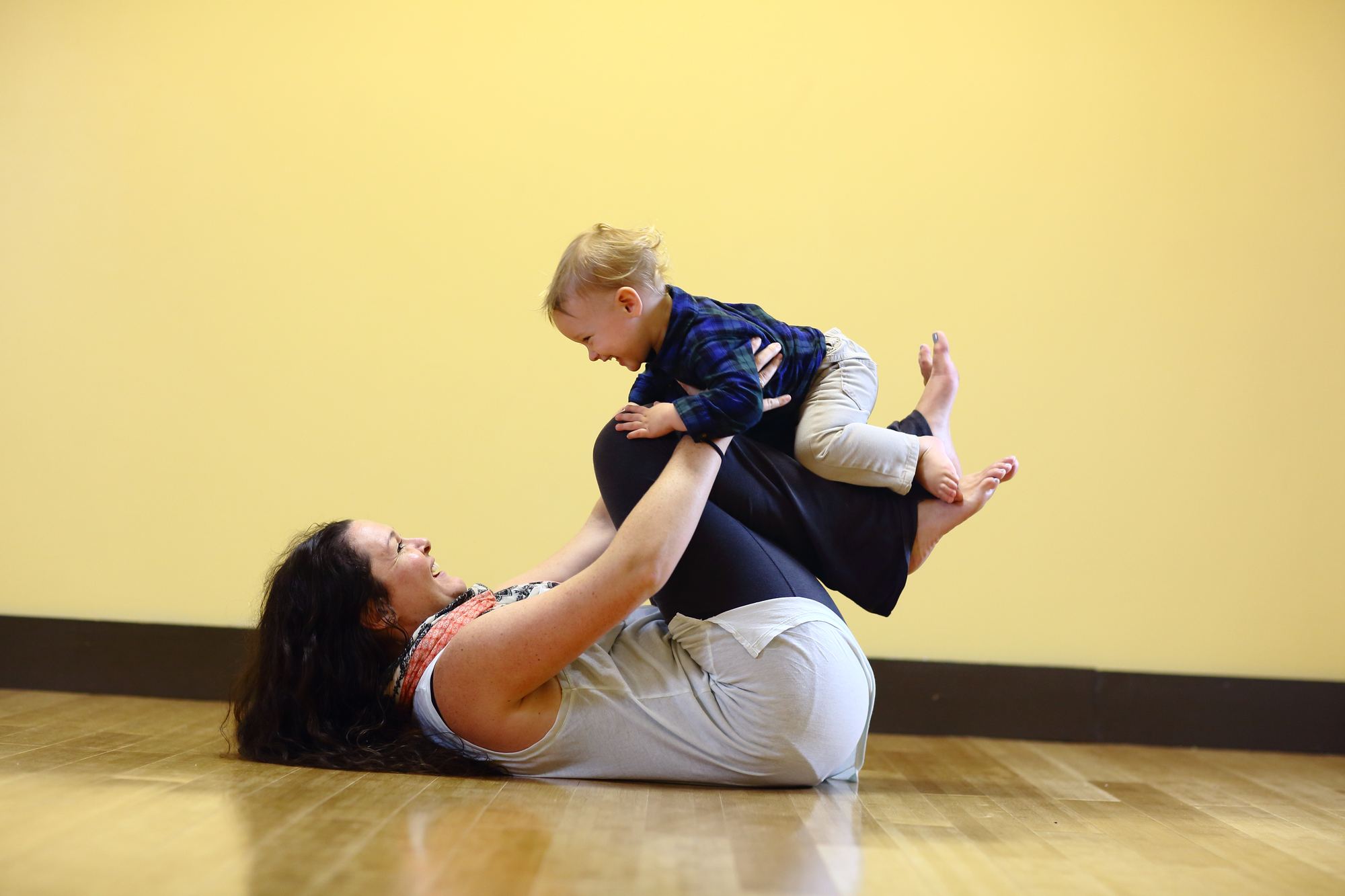 Mommy and Me yoga: mother lifting her toddler in airplane pose