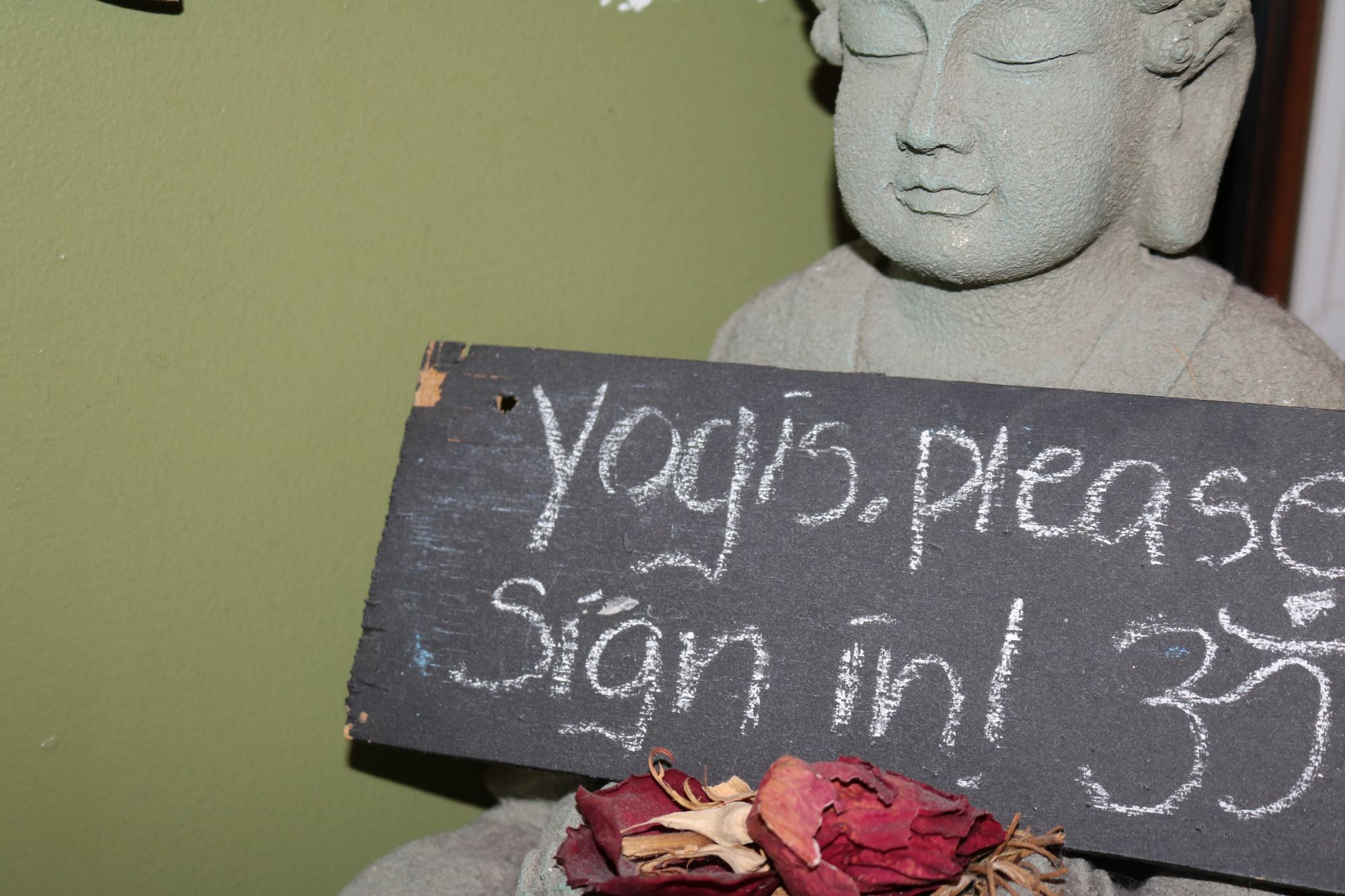 Buddha statue beside the Yogis, please sign in chalkboard at the studio front desk