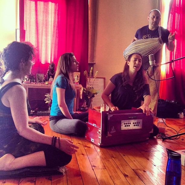 Kirtan with harmonium, group seated by altar