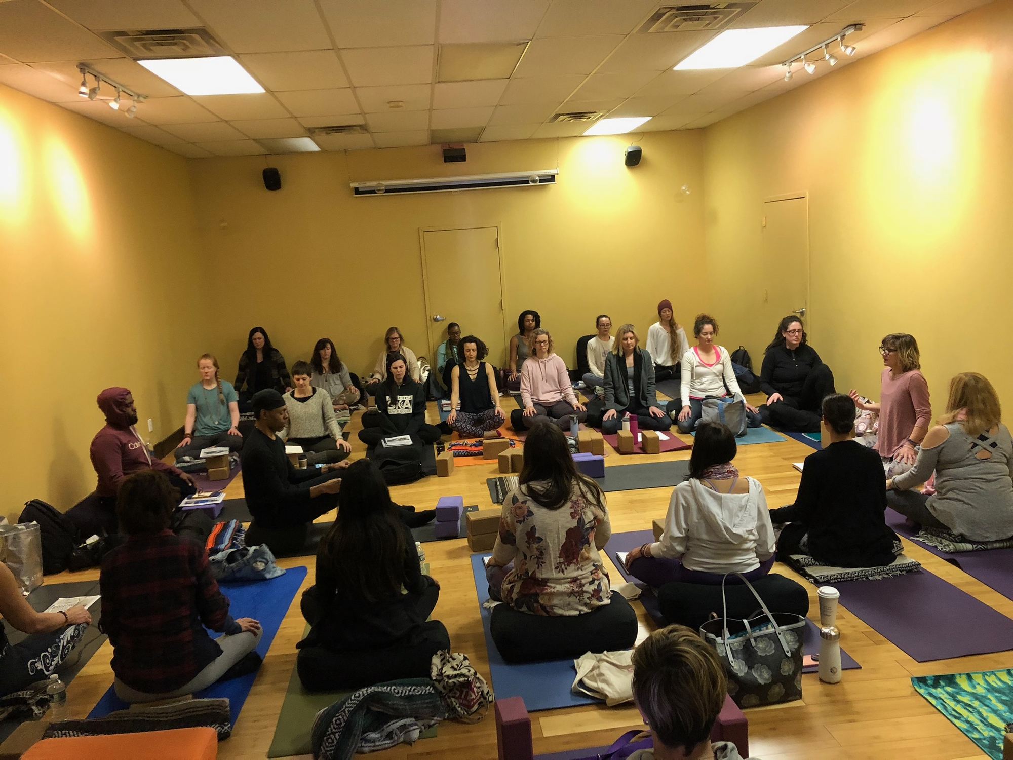 Group seated in meditation during a private wellness session in the studio