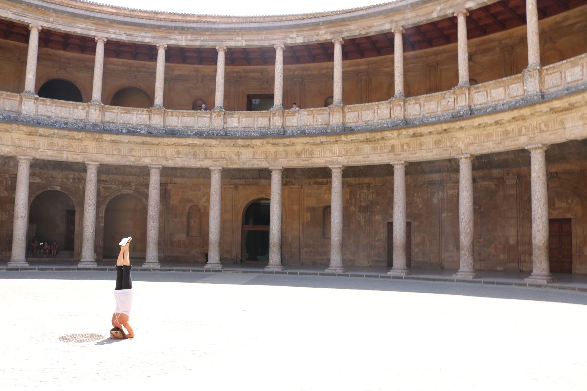 Yogi in headstand in a historic circular stone courtyard