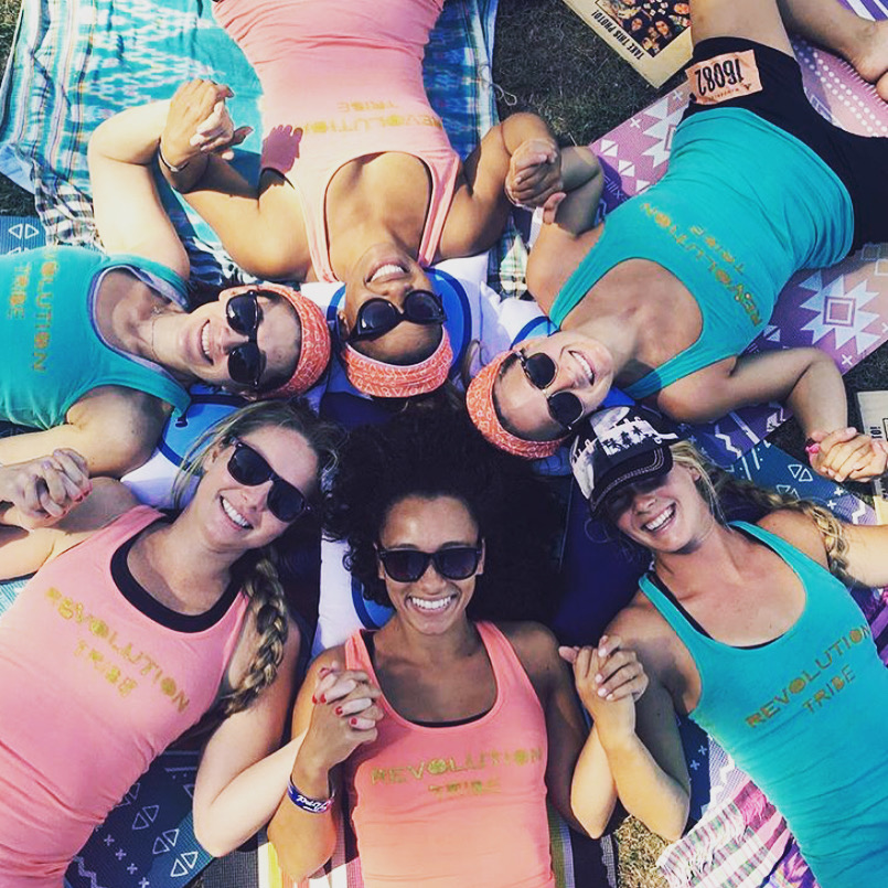 Revolution Yoga teachers lying in a circle, heads together, smiling