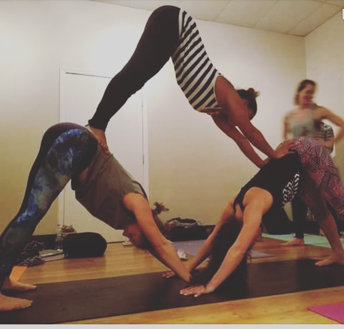 Teacher trainees practicing partner downward dog in the studio