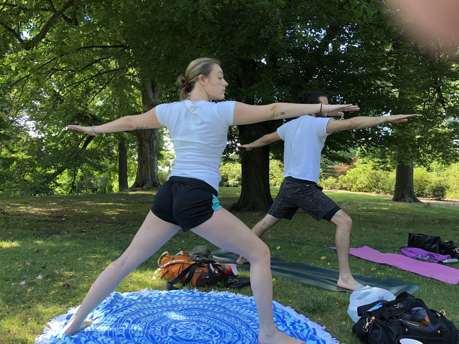 Two yogis in warrior II outdoors on the grass
