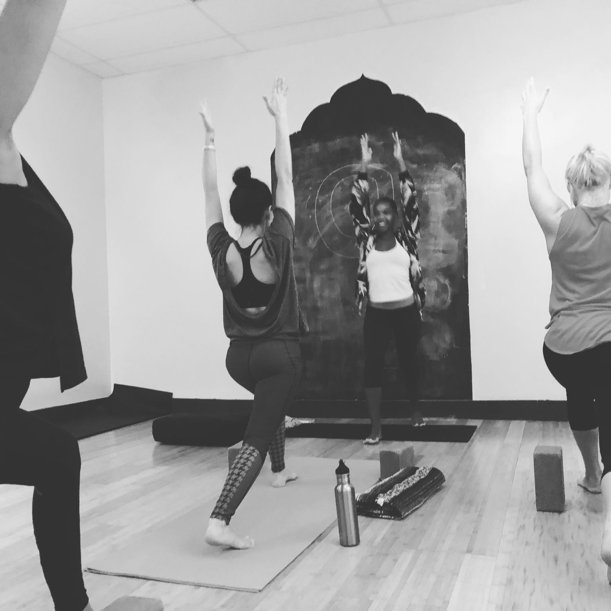 Black-and-white photo of a yoga class reaching arms overhead