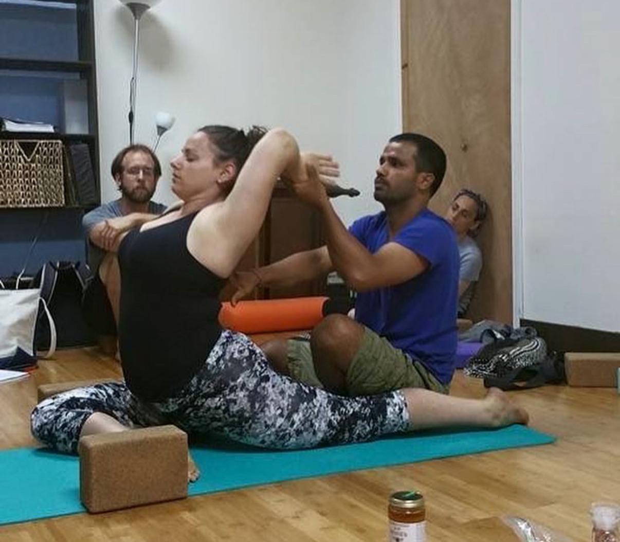 Lead teacher demonstrating a hands-on assist in a seated twist