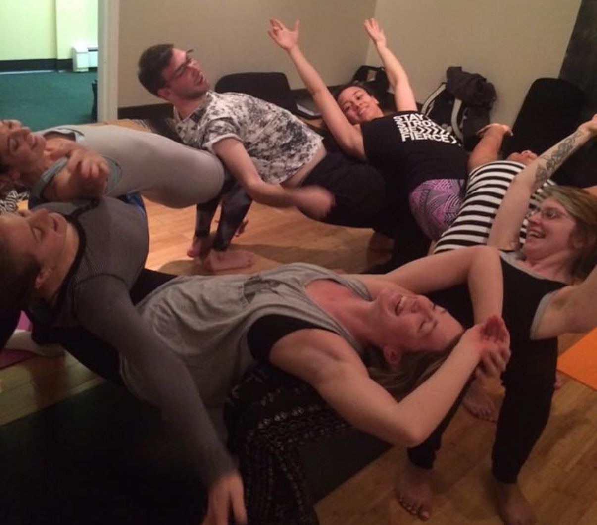 Teacher trainees laughing while practicing partner stretches