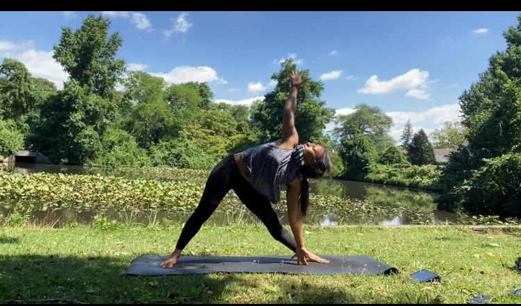 Triangle pose outdoors by a pond during a summer workshop