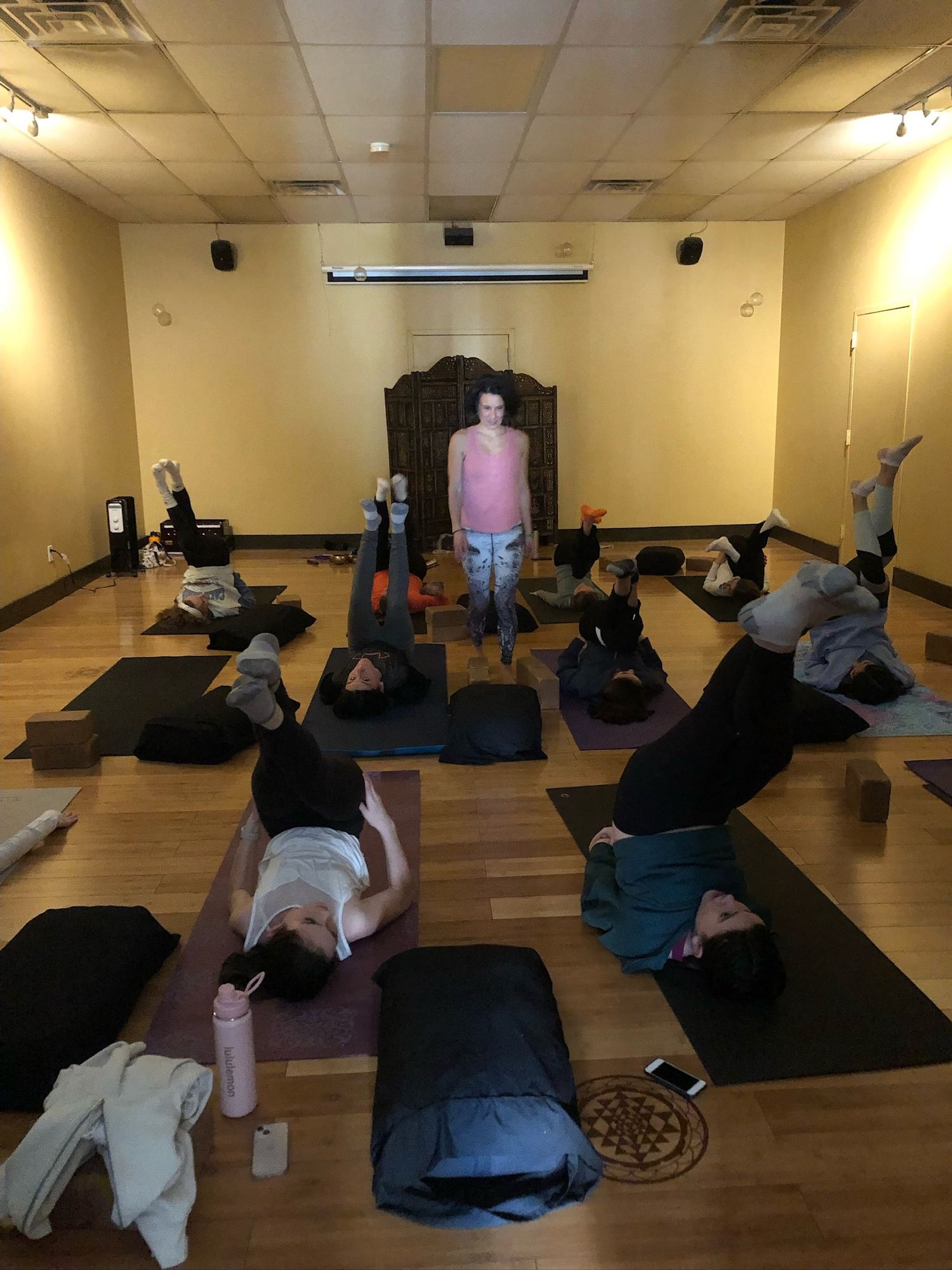 Teacher Micheline walking through class. students in shoulder stand