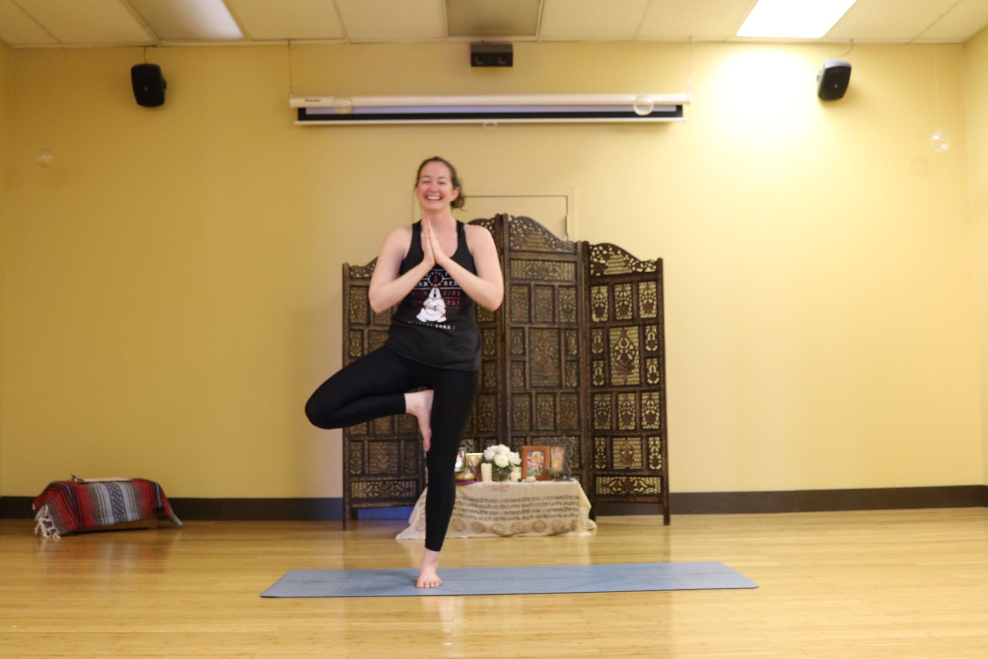 Private yoga session: student in tree pose with hands at heart
