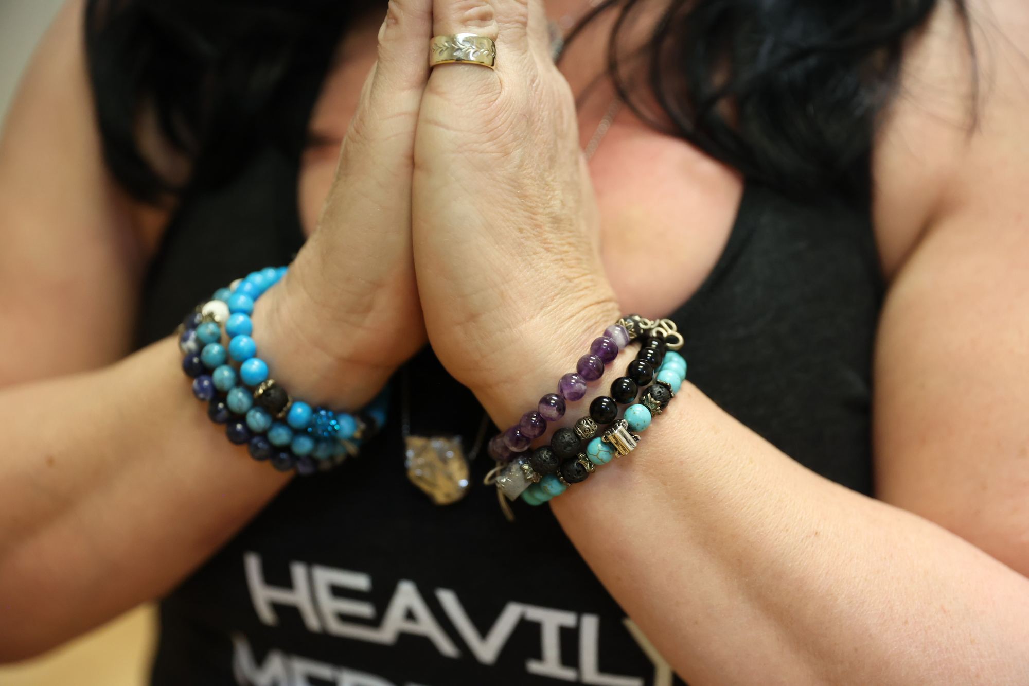 Hands in prayer position with gemstone mala bracelets