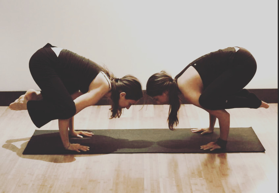 Two yogis in crow pose facing each other