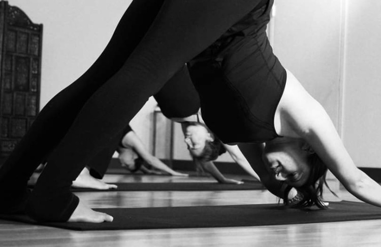 Black-and-white photo of students smiling in downward dog