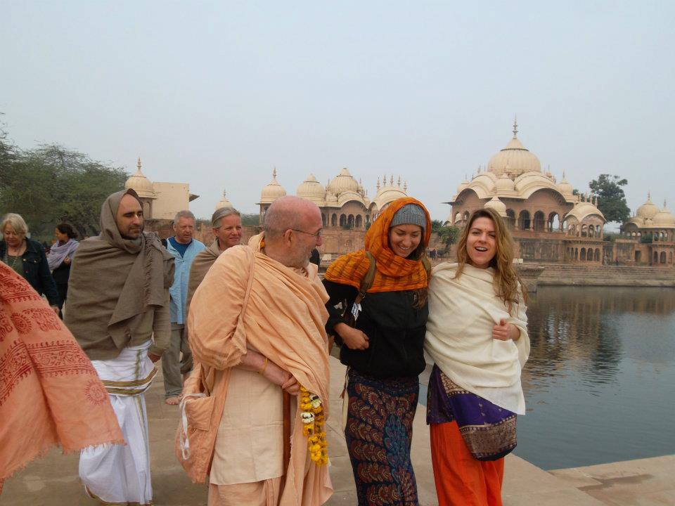 Revolution Yoga retreat group with a monk beside a temple lake in India