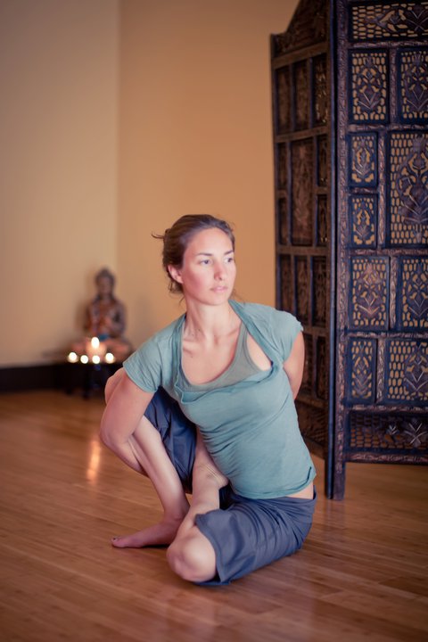 Amanda DiGiovanna, founder of Revolution Yoga, in a seated twist in the studio