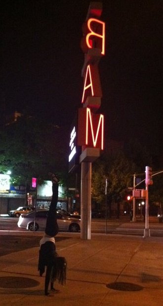 Amanda DiGiovanna in a handstand at night beneath a BAM sign