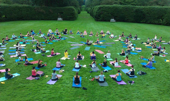 Amanda DiGiovanna leading a large outdoor yoga class on a lawn