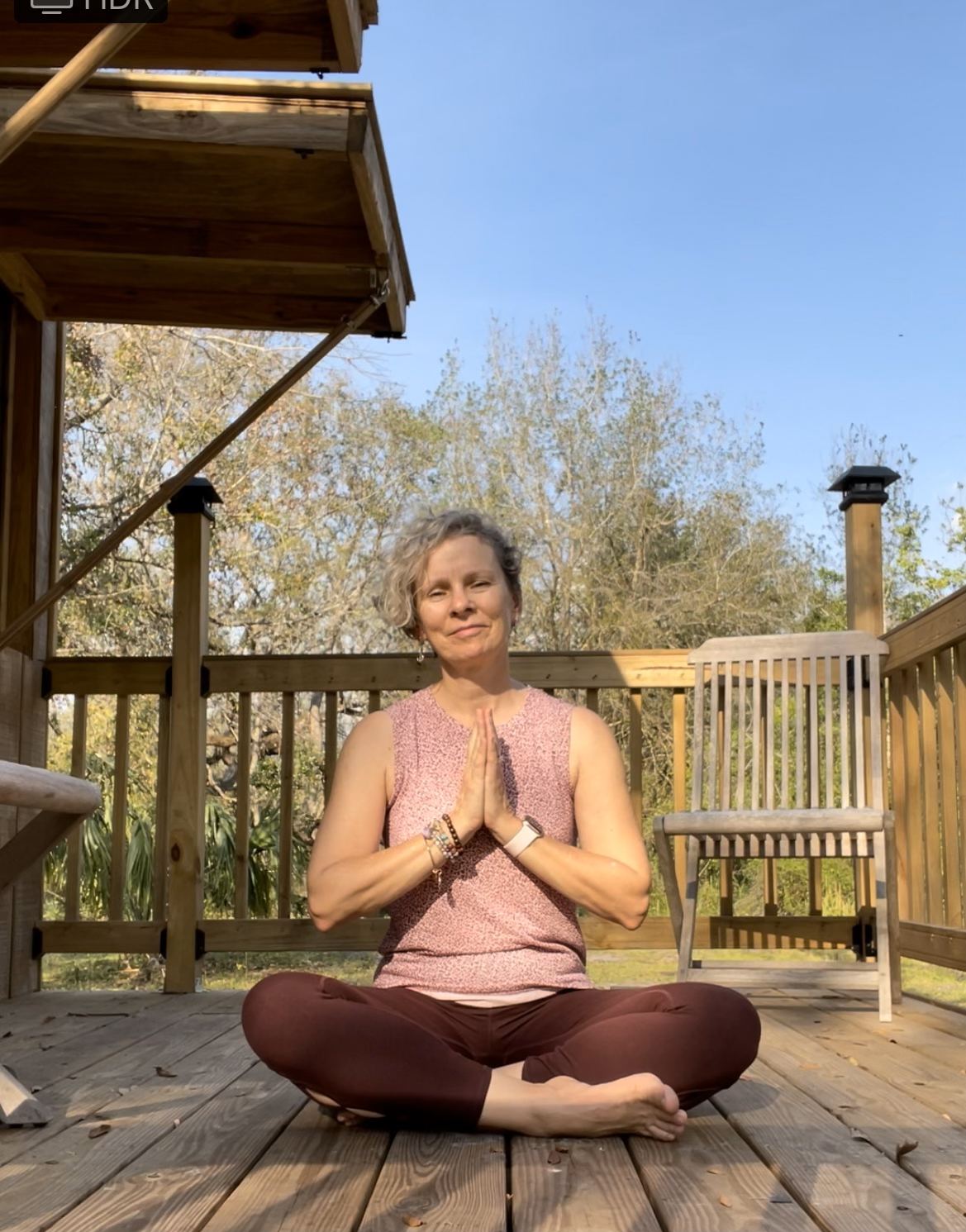 Jacqui Byrne seated on a deck with hands at heart
