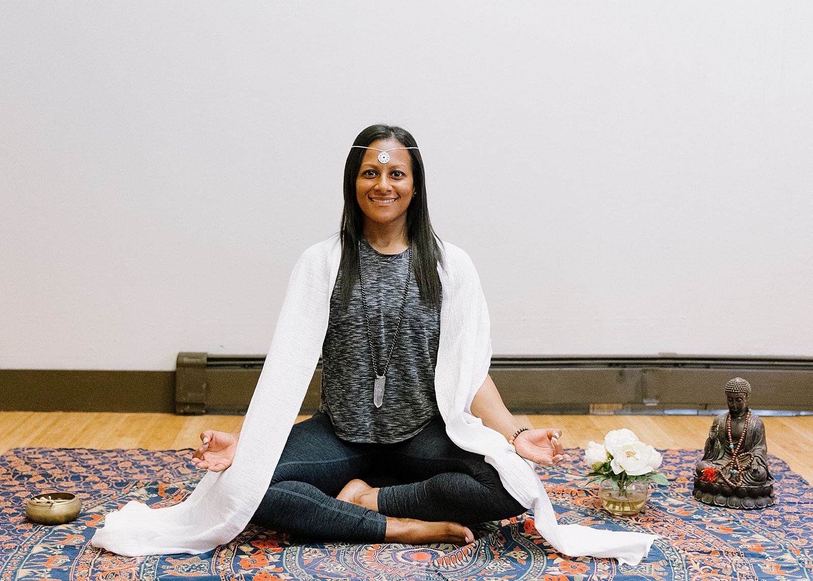 Jen Myers, yoga teacher, seated in meditation with a white shawl