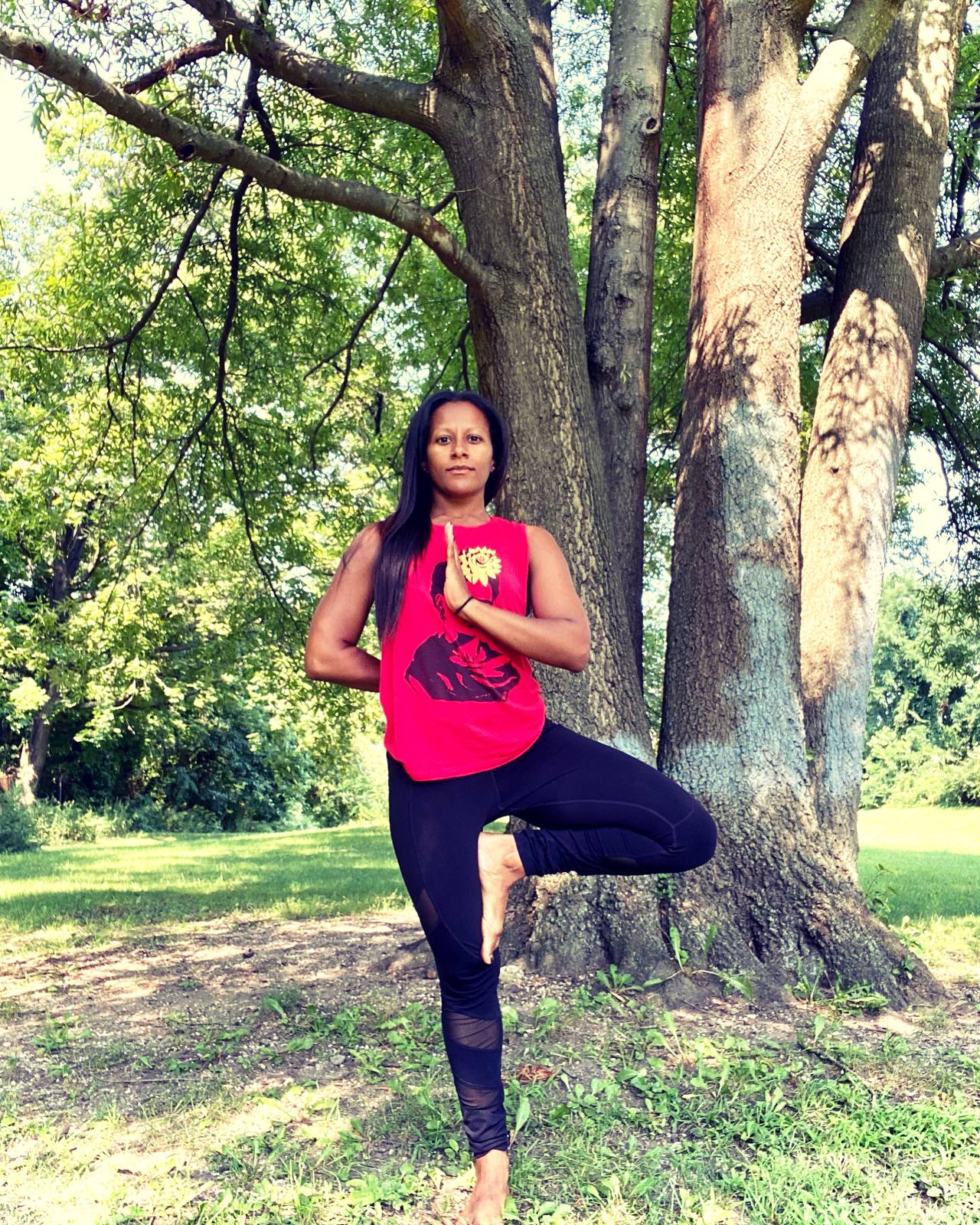Jen Myers in tree pose beside a tree
