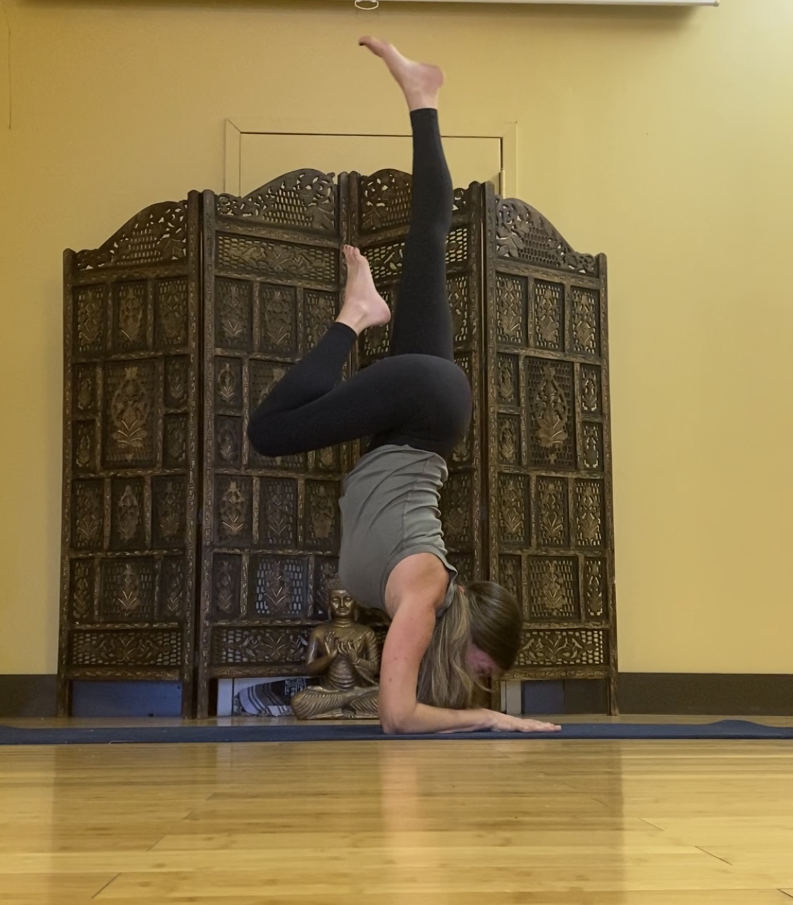 Jodi Langevin in headstand in front of the carved studio screen