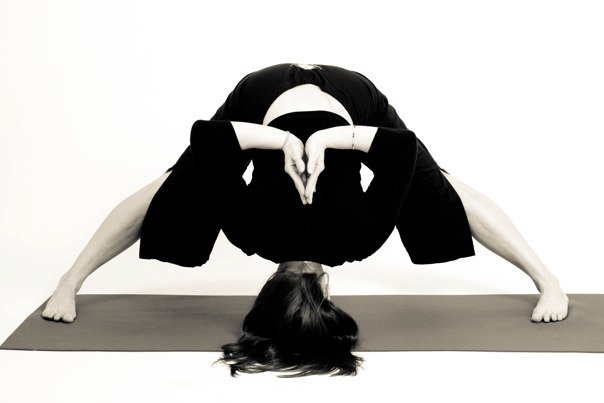 Lisa Ries in a wide-legged forward fold, black and white