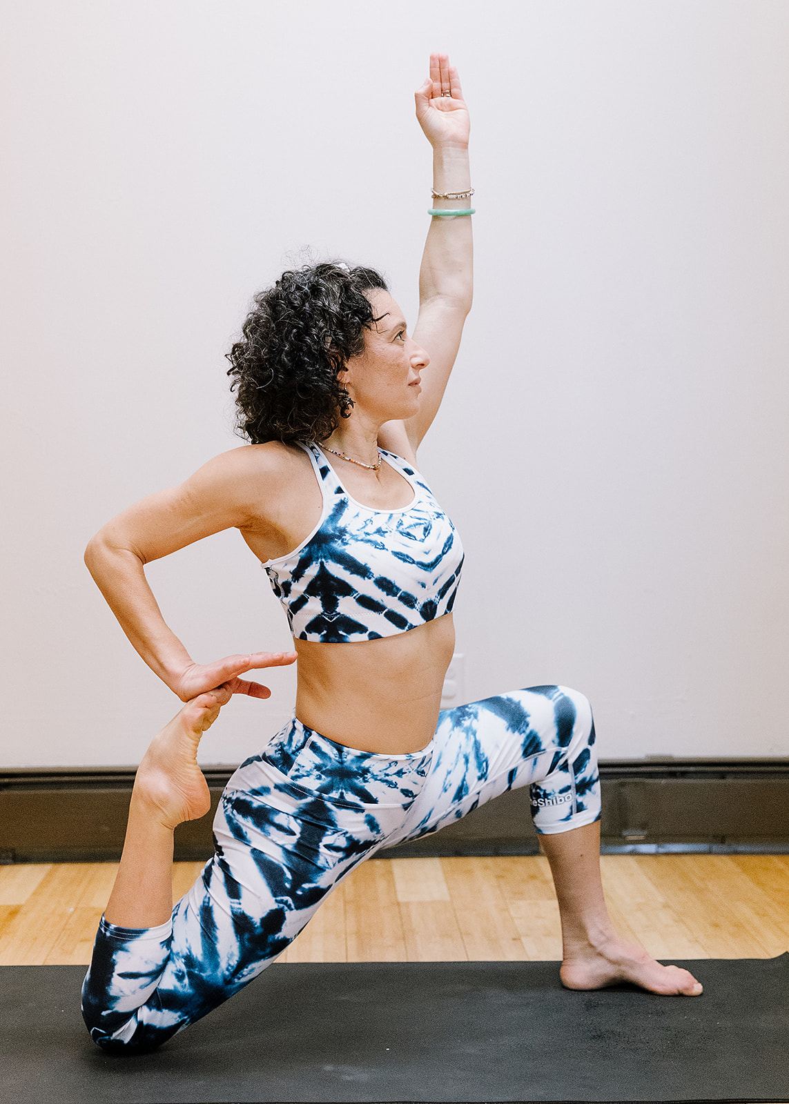 Micheline DeBono in a crescent lunge with one arm raised