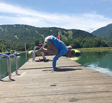 Michelle Levitsky in crow pose on a lakeside dock