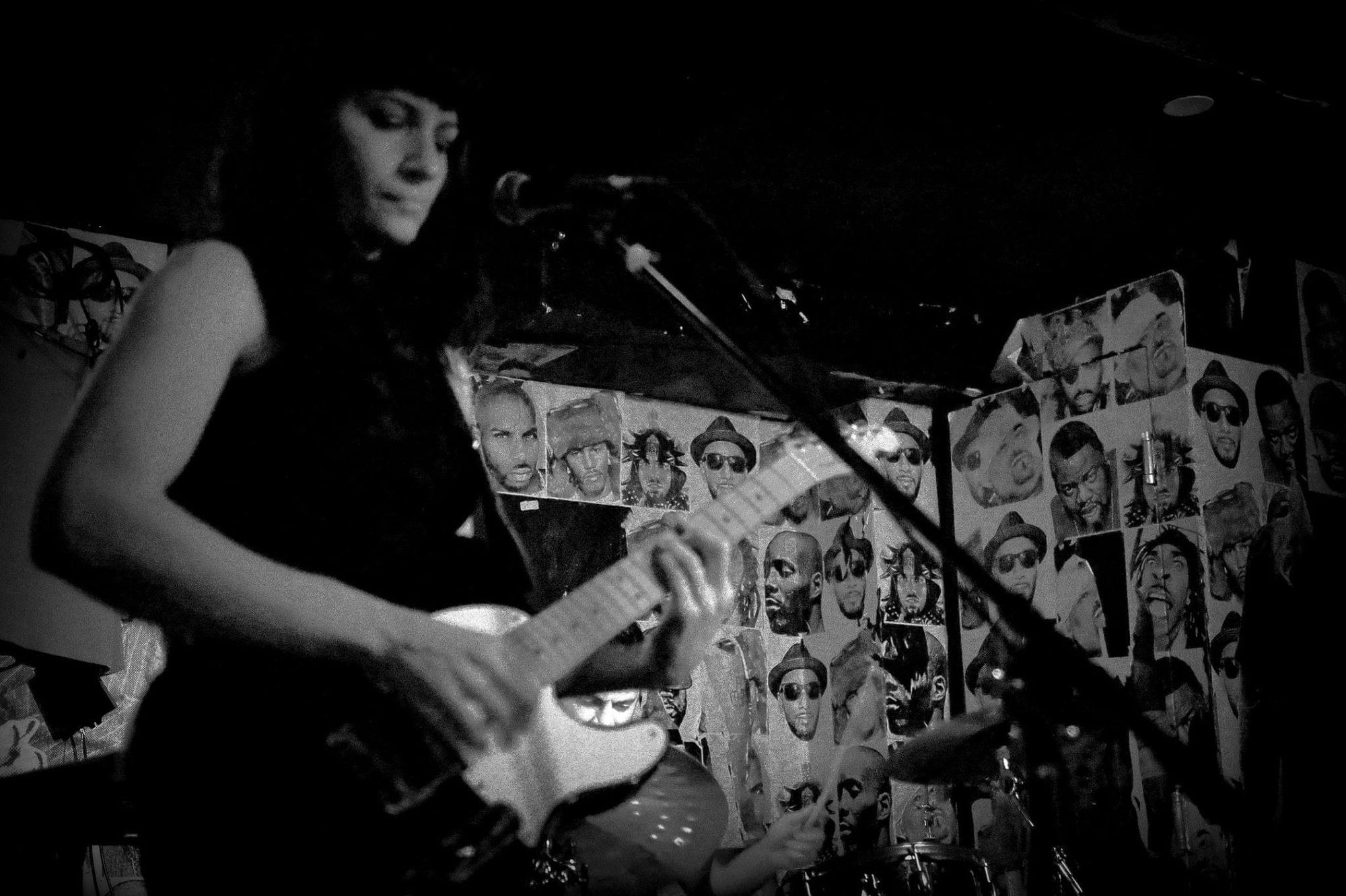 Paola Luna performing with her guitar, black and white