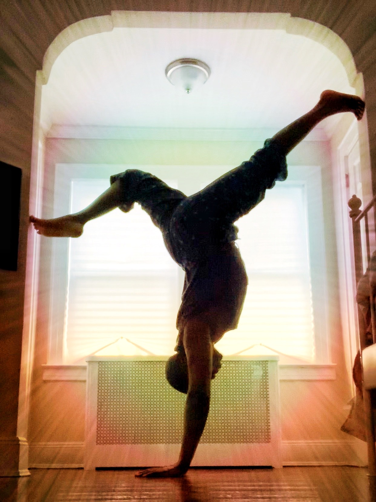 Rahmon Habeeb in a handstand split in a sunlit doorway